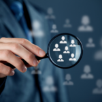 Professional holding magnifying glass focusing on people icons.