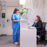 Clinical staff member in scrubs speaking with a patient experience manager.