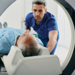 A doctor in blue scrubs scans an elderly patient lying in a CT machine.