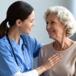Nurse in blue scrubs shares warm moment with smiling elderly patient.