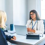 Female physician with stethoscope listens attentively to patient.