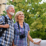 Older couple sightseeing abroad with backpacks and a camera.